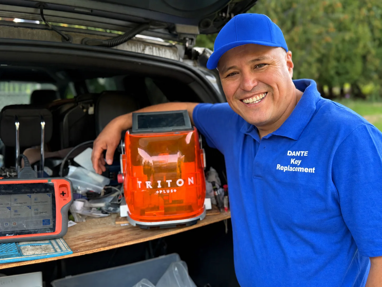 Dante beside the Triton Plus key cutting machine and a key programming tablet, set up in the back of his service vehicle.
