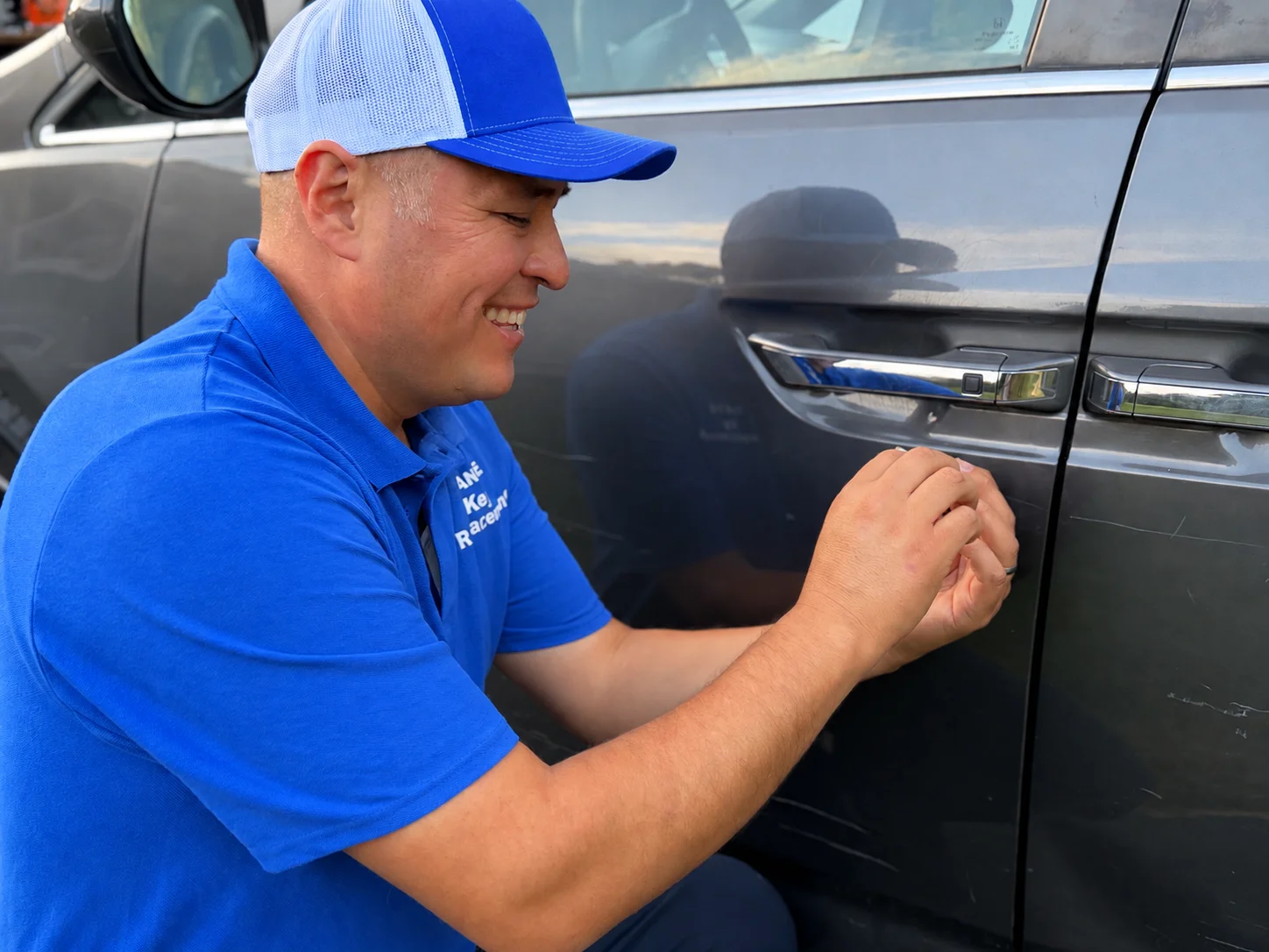 Dante crouched beside the driver door of a vehicle, working on it with a slim entry tool.